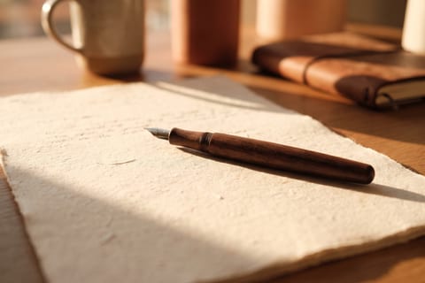 A heavy paper document with a fountain pen laid across it